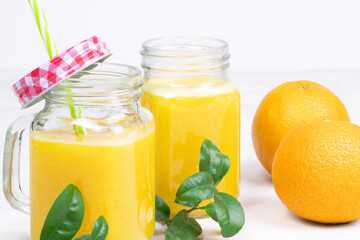Orange juice and green leaves on a white background.A glass of orange juice Healthy food. Vegan food
