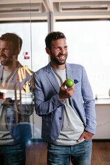Fototapeta premium Businessman in conference room eating apple. Young businessman having healthy snack.