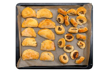 Frozen baked patties and dumplings in dough on a baking sheet on baking paper, isolated on a white background with a clipping path, top view.