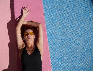 Girl sunbathing on pink border of swimming pool.