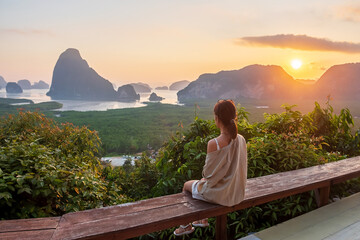 Happy traveler woman enjoy Phang Nga bay view point, alone Tourist sitting and relaxing at Samet Nang She, near Phuket in Southern Thailand. Southeast Asia travel, trip and summer vacation concept