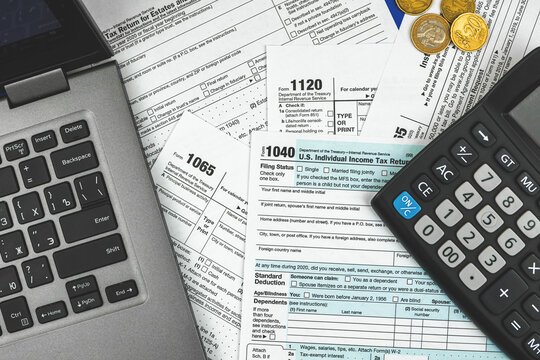 Financial background of Tax form 1040 income and return concept, accountant filling form, calculator and laptop on office desk