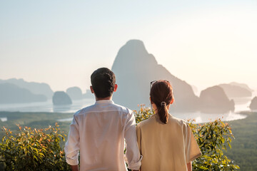 Happy couple traveler enjoy Phang Nga bay view point, Tourists relaxing at Samet Nang She, near Phuket in Southern Thailand. Southeast Asia travel, trip, love, together and summer vacation concept - obrazy, fototapety, plakaty