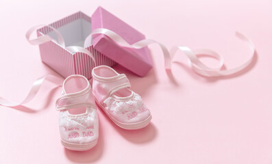 Obraz na płótnie Canvas It’s a girl announcement. Baby girl pink shoes on pink color background. Baby shower, christening concept.