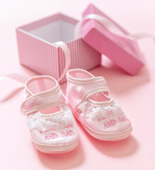 It’s a girl announcement. Baby girl pink shoes on pink color background. Baby shower, christening concept.