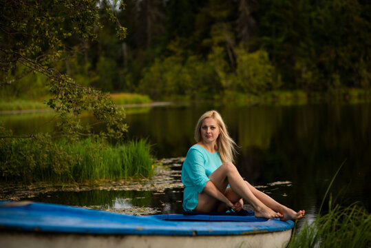 blonde girl sitting on a blue boat by the water, selective focus