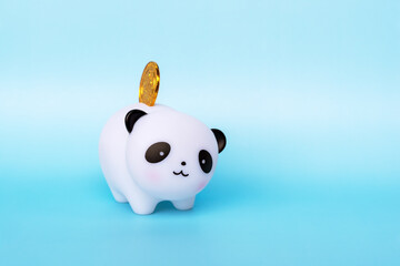 Coin bank panda on blue background with copy space