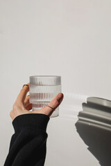 Woman's hand holds a glass of clean water over the white wall