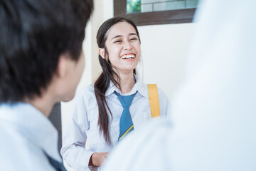 close up of smiling beautiful girl and friends in high school uniform discussing in the corridor of the school building