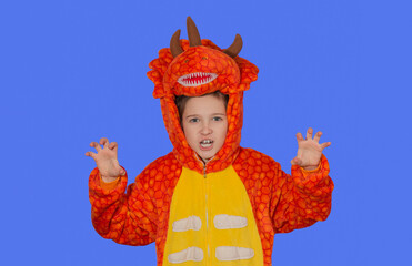 boy in dragon pajamas growls at camera on blue background