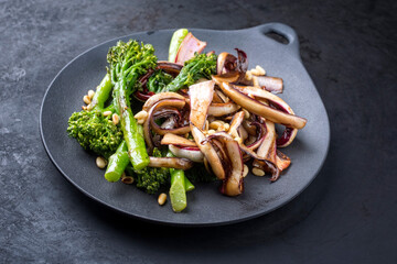 Modern style roasted rapini broccoli rabe and caramelized radicchio tardivo with pine nuts served...