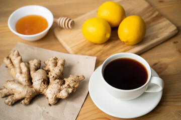 Overhead of glass cup with ginger and lemon tea, teapot, white wooden background.