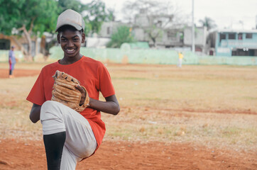 boy with brown skin and latin origin playing baseball in the park with ball, glove and bat, dark...