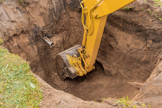 Hydraulic excavator piston digs deep pit in industrial area on construction site
