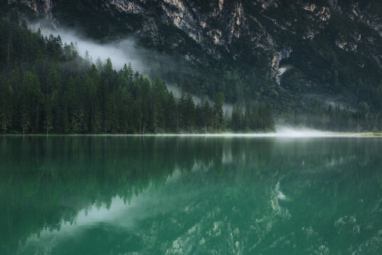 Fototapeta Mountain and forest in the fog reflected in the lake