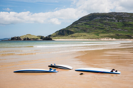 Surfboards lying on the empty beach with mountain in the background