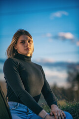 Portrait of a young beautiful blonde girl against the background of the sky.