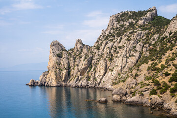 Fototapeta na wymiar Stone rock on the coast of the peninsula in Alanya (Turkey) - view from the sea. High bare desert steep cliff among the blue waters of the Mediterranean Sea, close-up