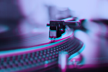 Obraz na płótnie Canvas Retro dj turntable playing vinyl record with music. Professional disc jockey turn table player device edited with 3d anaglyph filter in purple color