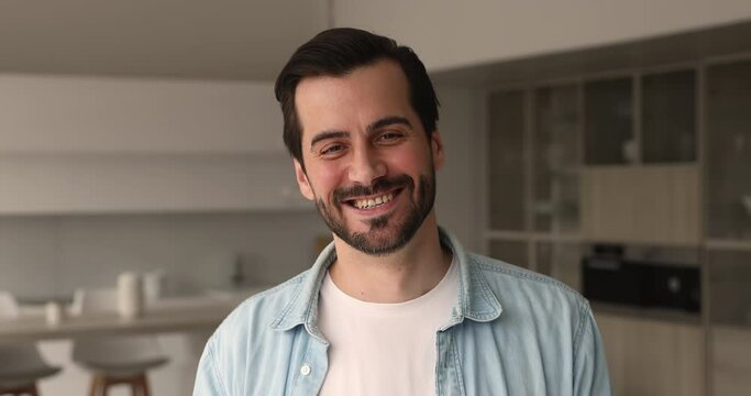 Head shot confident handsome 30s man pose at home in living room alone smile look at camera. Professional occupation person, satisfied client of services, blogger and freelancer male portrait concept