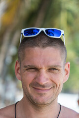 Portrait of a young man with sunglasses resting on the beach, close up