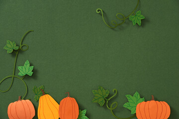 Autumn leaves and pumpkins border frame with space text on green background.