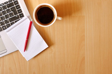 Laptop with coffee cup, notebook and pen on wooden background, concept for home office. Business concept. Work from home. desk office with laptop, blank notepad, coffee cup and pen on wooden table.