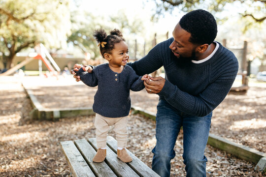 Portrait of a little girl holding her dad's hand as she walks at the park