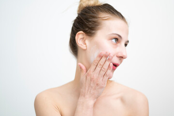 Happy Young Woman Applying Cream on Her Face, Studio Shot on White Background