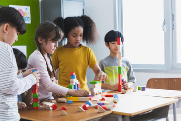 Diversity of school students playing wooden blocks in classroom