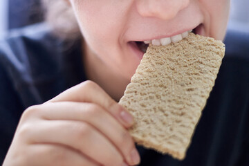 Woman holding a crisp bread in her hand, healthy eating concept.
