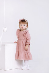 portrait of a little cute girl in a beautiful pink dress and bow on head is looking at the camera isolated on white background. adorable preschool age girl