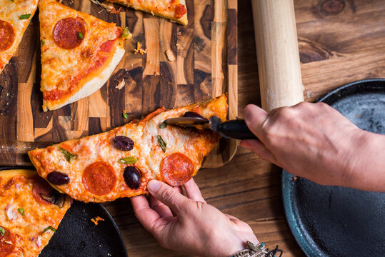 Woman's hand cutting homemade pizza