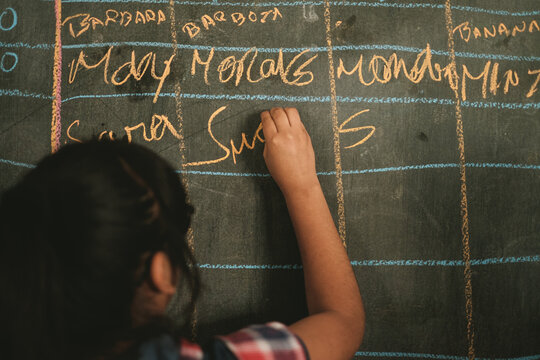 a young girl writing on the chalkboard