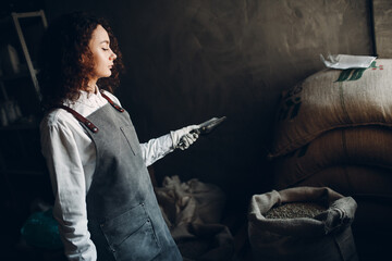Green coffee beans in burlap sack and woman roaster with scoop
