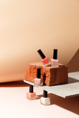Set of nail polish bottles neutral natural colors on brick podium on beige background. Concept of pallete for french manicure, trendy modern stone platform for presentation of products