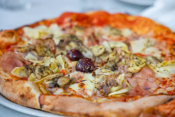 homemade pizza with ham, olives and artichoke