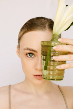Sensual portrait of a young blond girl with a litle vase and a lily in it