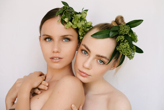 Sensual portrait of two young girls with flower composition on their heads