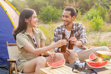 Enjoy young asian woman, girl and man cheering with bottle of beer, sitting on chair outside the tent. Adventure couple, people camping in forest. Eco activity, lifestyle in nature on summer, concept.