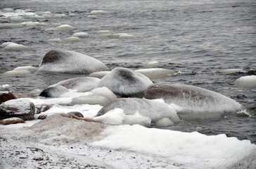 Fototapeta premium Frozen stones with ice. ice glaze Waves in a bay lake or sea. near shore. Sunset