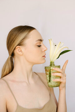 Sensual portrait of a young blond girl with a litle vase and a lily in it