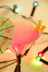 cosmopolitan cocktail with umbrella and colourful party lights