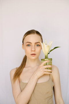 Sensual portrait of a young blond girl with a litle vase and a lily in it