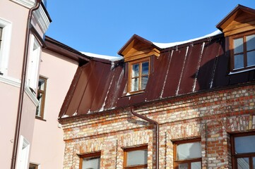 Corner of the courtyard of old building houses with windows attic and downpipe 