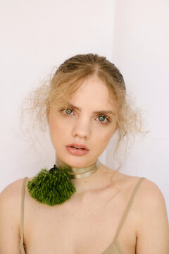 Sensual portrait of a young blond girl with a fluffy flower on the neck