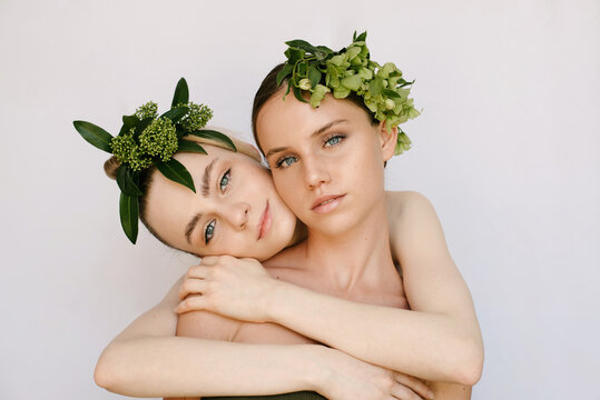 Sensual portrait of two young girls with flower composition on their heads