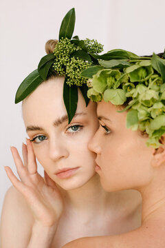 Closeup sensual portrait of two young girls with flower composition on their heads