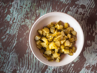 Chopped pickled cucumbers in a deep white plate for making salad