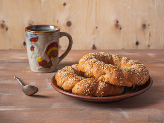 Breakfast with butter rolls with sesame seeds t tea in a large ceramic mug